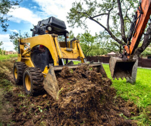 Yellow mini bulldozer working with earth, moving soil and doing landscaping works